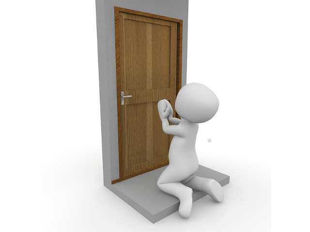 Illustration d'un personnage sans caractéristiques distinctes tentant d'ouvrir une porte en bois fermée.